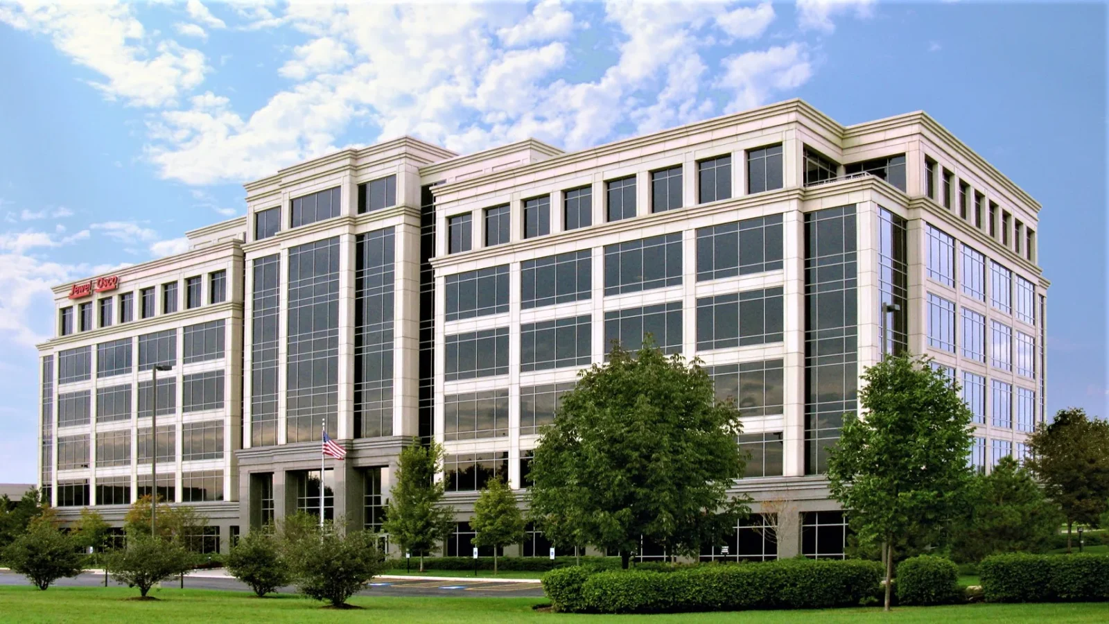150 Pierce Rd, a six-story office building clad in cream precast concrete with tall bands of dark glass, seen across landscaped lawn in Hamilton Lakes.