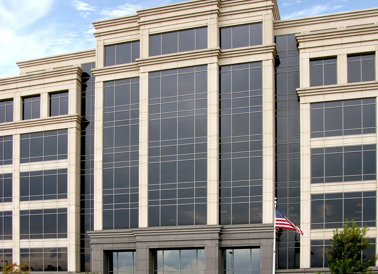 Main entry elevation with a dark granite base, glass entrance doors and a precast frame around the full-height window bay, with a flagpole in front.