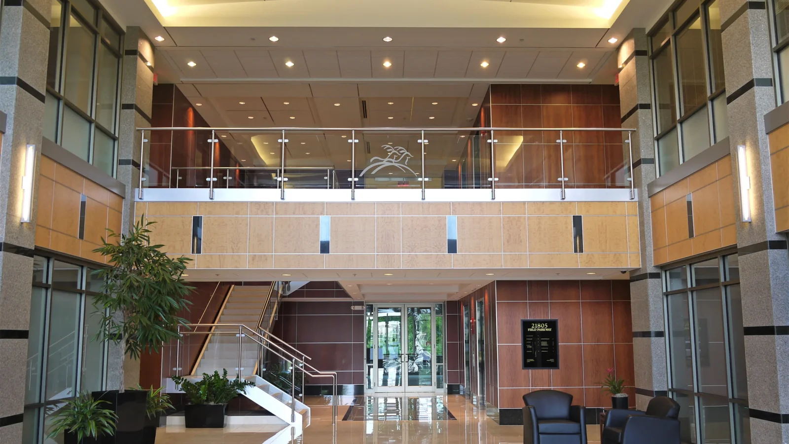 Two-story lobby with granite-clad piers, maple and cherry wood panels, a glass-railed mezzanine and polished stone floor.