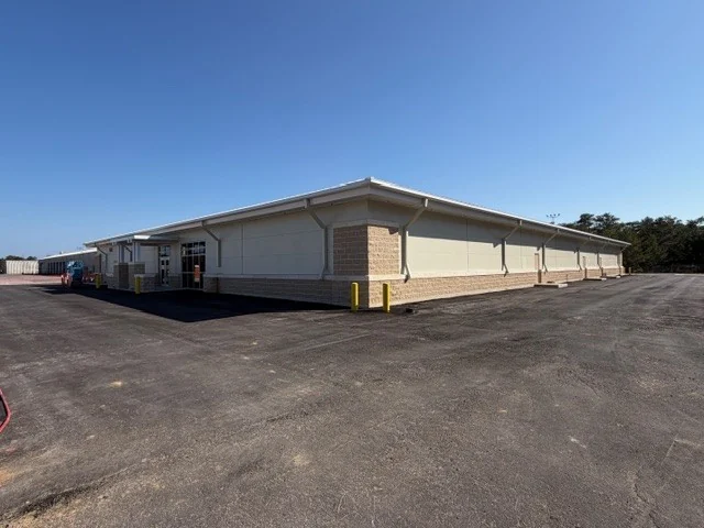 The Eglin AFB test facility seen from a corner of its new parking area, its long elevations running back under a standing-seam roof.