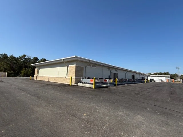 The full length of the Eglin AFB test facility from across the paved lot, pines behind it.