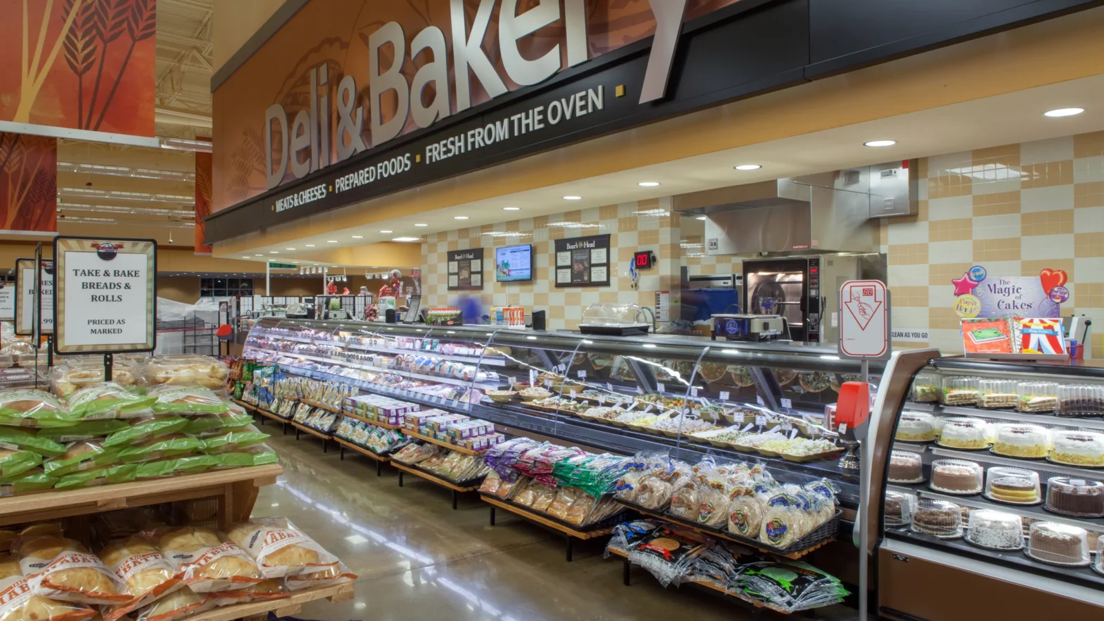 The Deli and Bakery: a curved, backlit sign over refrigerated cases and a tiled service wall.