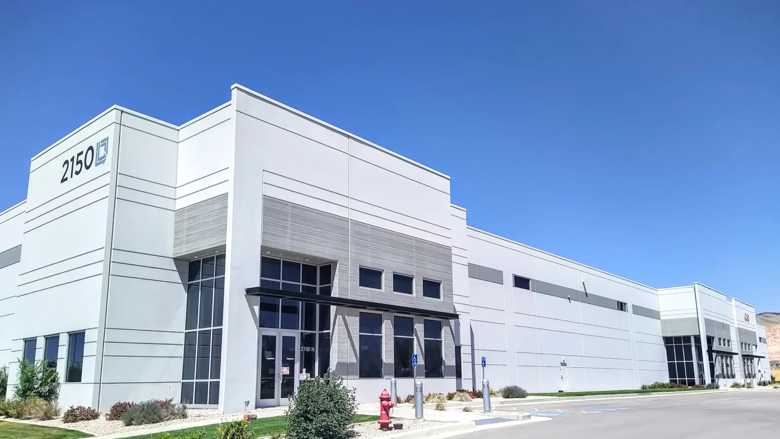 I-215 Logistics Center's 2150 building, with a glazed two-story office entry, black steel canopy and banded grey tilt-up panels.