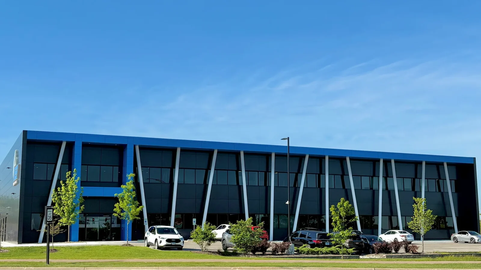 MEI System USA Headquarters, a two-story office front in dark metal panel with a bright blue cornice and a row of angled white columns.