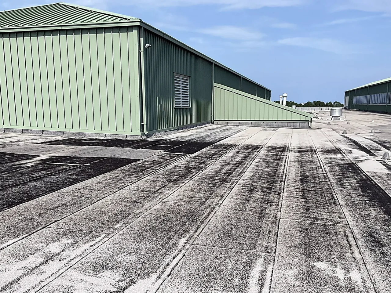 Pensacola B626 Hurricane Sally Repairs project files: the low-slope roof and green metal high bays of Building 3460 at NAS Pensacola, surveyed June 2025.
