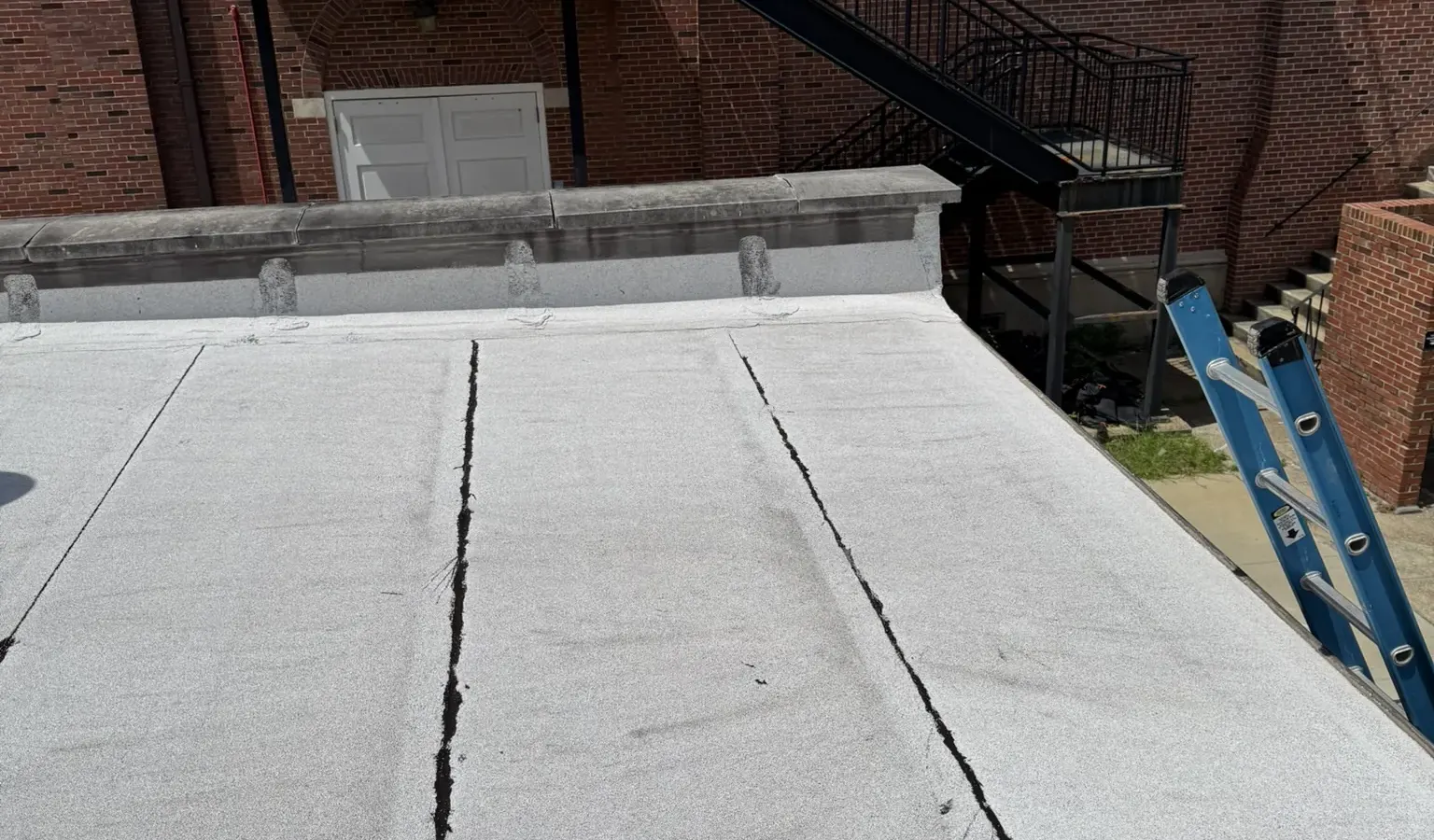 The low-slope roof and parapet of a small boiler building at NAS Pensacola, against the brick academic building it serves.