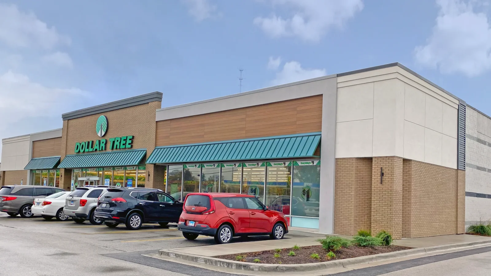 Refreshed Dollar Tree facade with a brick sign tower, teal metal awnings, wood-look cladding band and a cream panel corner.