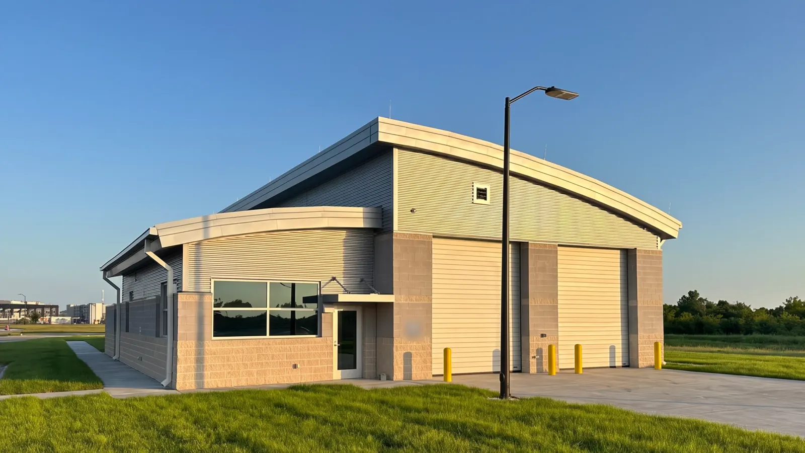 The inspection building at the Tyndall AFB commercial gate in early light, its office window, entry canopy and overhead doors facing a green lawn.