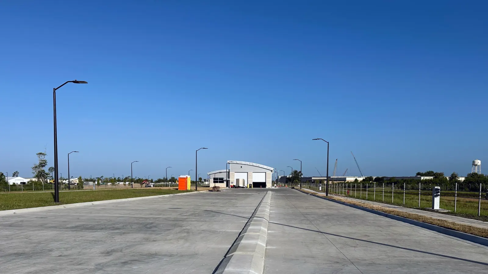 The new approach lanes of the Tyndall AFB commercial gate, a long concrete roadway with a center curb and street lights leading to the inspection building.