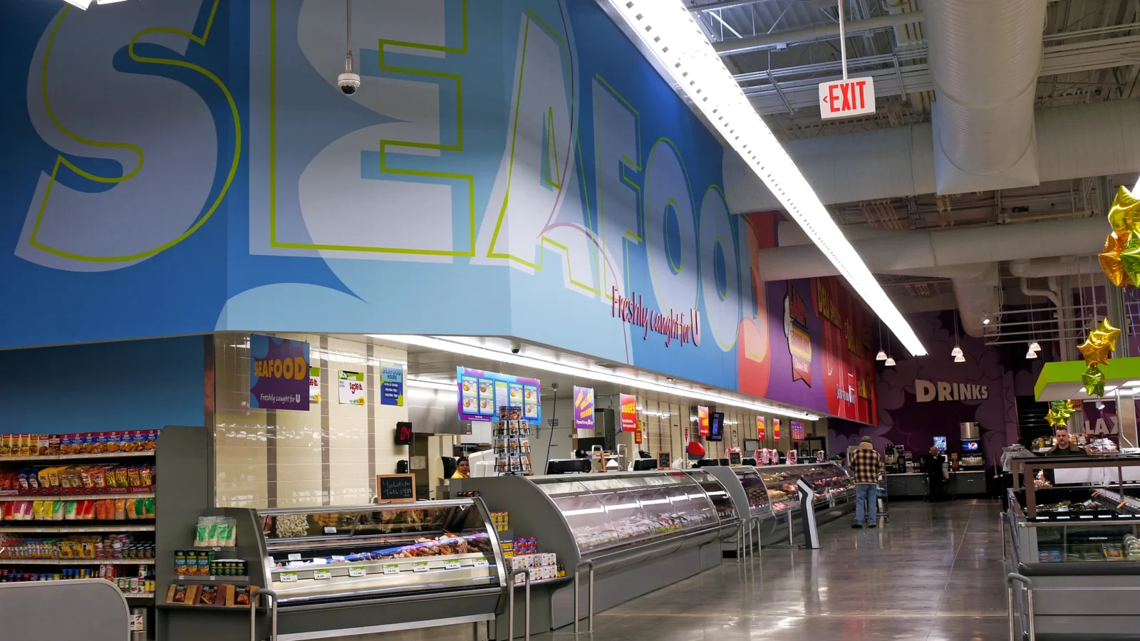 Seafood service counter with curved glass cases beneath a large blue Seafood supergraphic running along the store's back wall.
