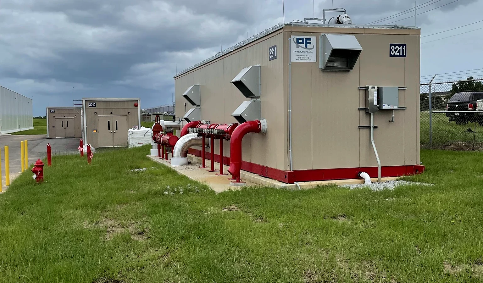 The fire pump house beside the hangar, with red fire-protection piping entering the building at grade.