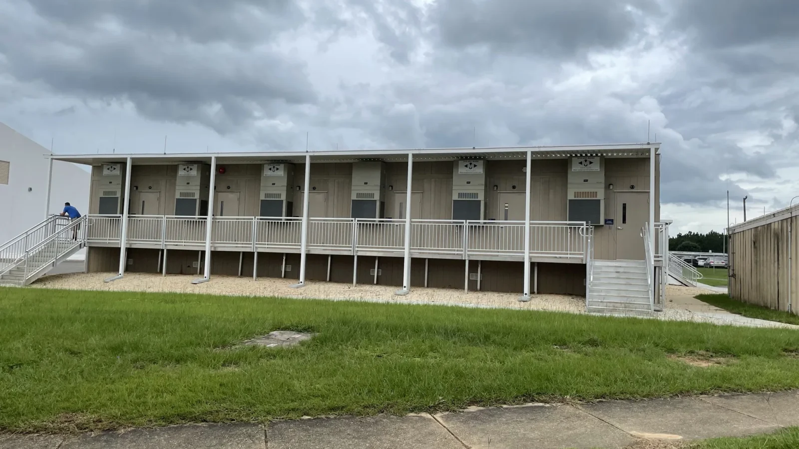 The single-story modular support building beside the hangar, with a covered walkway, railings and entry stairs along its length.