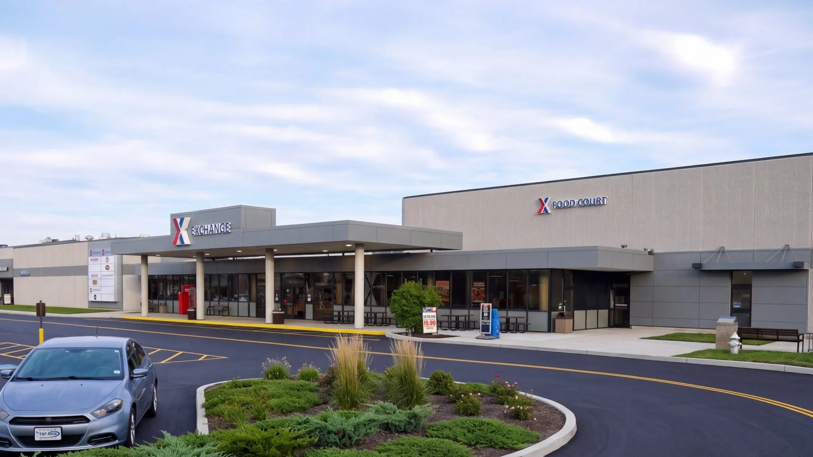 The remodelled Wright-Patterson Exchange seen obliquely across the parking lot, with the entry canopy at left and the Food Court wing extending to the right past new landscaping.